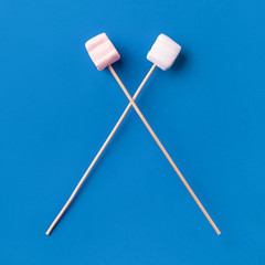 marshmallows on wooden sticks, over blue background, marshmallow icon