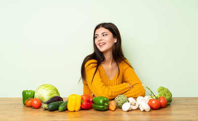 Fototapeta premium Teenager girl with many vegetables with arms crossed and happy