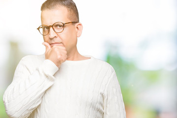 Middle age arab man wearing glasses over isolated background looking confident at the camera with smile with crossed arms and hand raised on chin. Thinking positive.