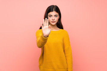 Teenager girl  over isolated pink wall making stop gesture