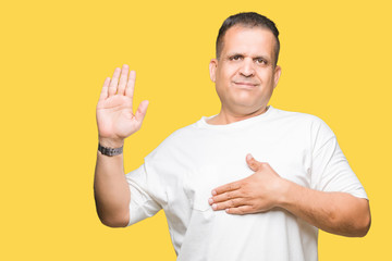 Middle age arab man wearig white t-shirt over isolated background Swearing with hand on chest and...