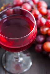 glass of red wine and grapes on black wooden table background