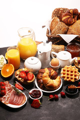 Fototapeta na wymiar Huge healthy breakfast on table with coffee, orange juice, fruits, waffles and croissants. Good morning concept.