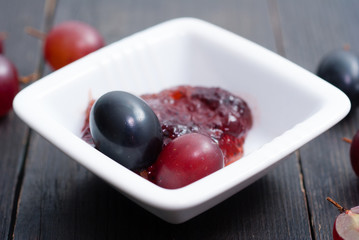 grape jelly and red grapes on black wood table