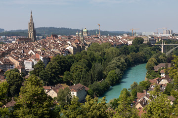 Fototapeta na wymiar A cityscape of Bern, view over the rooftops of the historic Old Town, the Münster (Minster) and the loop in the Aare river