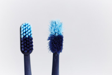 New and used blue color toothbrush in cup on white