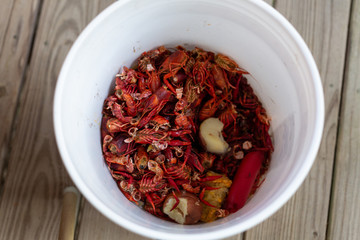 Crawfish heads and tails in white bucket with corn and potatoes