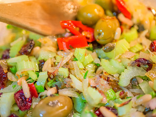 Close up of a vegetable based condiment for the famous Italian recipe “alla ghiotta”. Tomato, raisins, pine nuts, celery, red onion, oil and pepper.