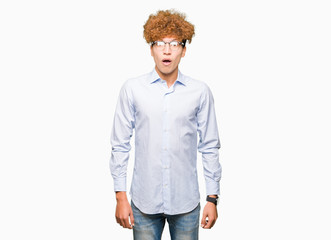 Young handsome business man with afro wearing glasses afraid and shocked with surprise expression, fear and excited face.