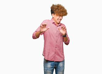 Young handsome business man with afro hair disgusted expression, displeased and fearful doing...