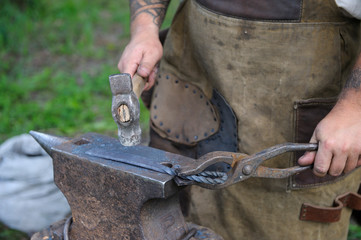 Blacksmith’s hand holds a hammer forging a metal billet on an anvil