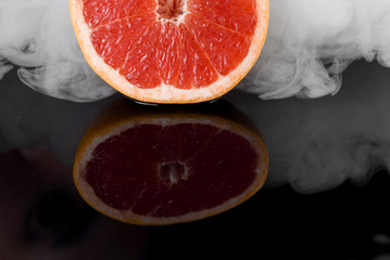Grapefruit with smoke on black background. Citrus fruit with smoke of hookah. Healthy freshness food. fruit with vitamin