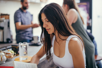 Urban girl reading book while sitting in coffee restaurant