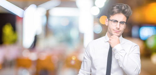 Young business man wearing glasses over isolated background looking confident at the camera with smile with crossed arms and hand raised on chin. Thinking positive.