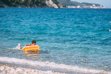 Boy playing in the sea with air mattress