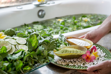 Woman preparing a natural herbal bath. Spa-treats: Regenerating herbal bath with lime slices,...