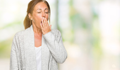 Beautiful middle age adult woman wearing winter sweater over isolated background bored yawning tired covering mouth with hand. Restless and sleepiness.