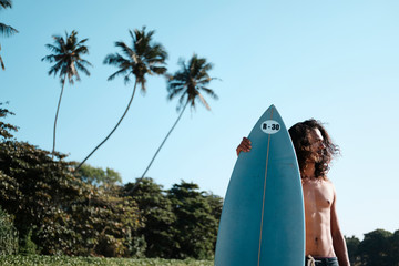 Man Surfer Sitting at Surfboard on Sand Beach