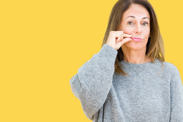 Beautiful middle age woman wearing winter sweater over isolated background mouth and lips shut as...