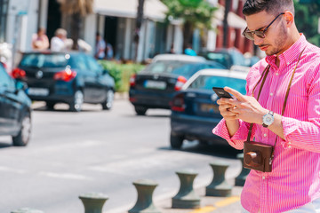 Stylish tourist calling a lift on his smartphone.