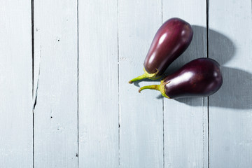 two eggplants with shade on bright wood table