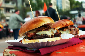 Organic Burger on street food festival in hand. Pulled pork or burger are sold on Open kitchen food festival event. Street food