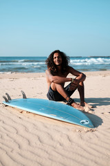Man Surfer Sitting at Surfboard on Sand Beach