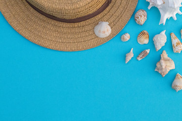 Fototapeta na wymiar Hat and shells on a blue background, summer mood