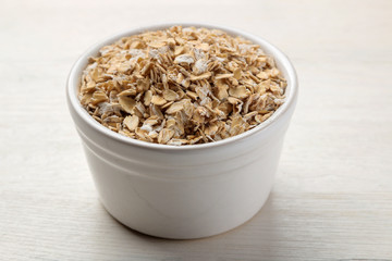 Dry oatmeal flakes in a bowl on a white wooden table. healthy nutrition. healthy food.