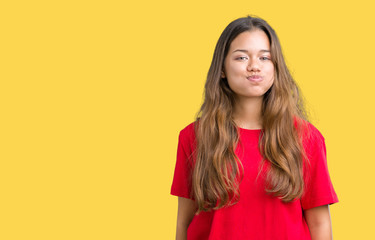 Young beautiful brunette woman wearing red t-shirt over isolated background puffing cheeks with...
