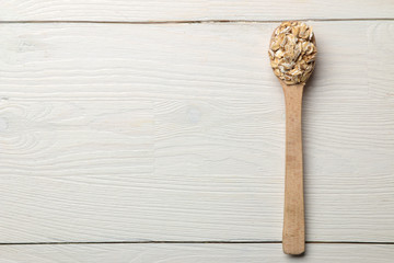 Naklejka premium Dry oatmeal flakes in a wooden spoon on a white wooden table. healthy nutrition. healthy food. top view