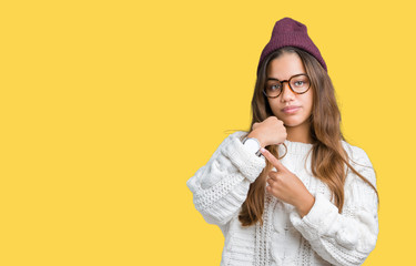 Young beautiful brunette hipster woman wearing glasses and winter hat over isolated background In...