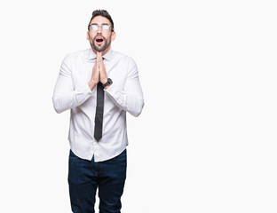 Young handsome business man wearing glasses over isolated background begging and praying with hands...