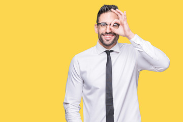 Young handsome business man wearing glasses over isolated background doing ok gesture with hand smiling, eye looking through fingers with happy face.