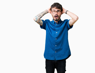 Fototapeta premium Young handsome man wearing glasses over isolated background Crazy and scared with hands on head, afraid and surprised of shock with open mouth