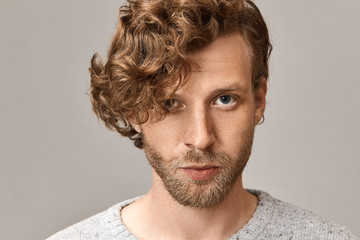 Headshot of handsome fashionable young blue eyed man with stylish ginger curls, freckles and...