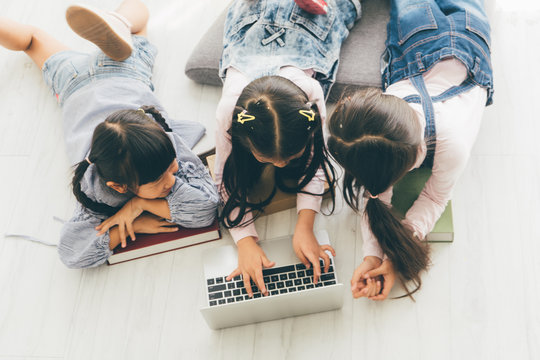 Three aisan children, Three sister, lay on the floor and use a laptop to do their schoolwork.children coding concept.