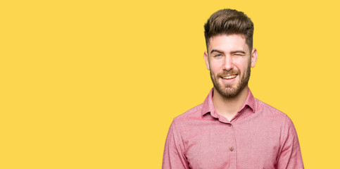 Young handsome business casual man winking looking at the camera with sexy expression, cheerful and...