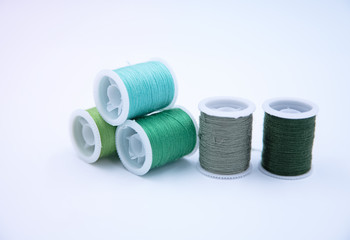 Roll of thread put on white background,group of green color,for needle work,blurry light around