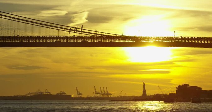 The Beautiful Manhattan Bridge In Incredible NYC With Silhouette of New York Statue Of Liberty Travelling on Hudson River At Sunset