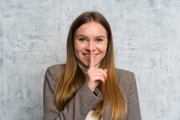 Young woman over grunge wall doing silence gesture