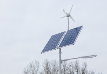 Solar panel, alternative electricity source, concept of sustainable resources. Solar panels and wind turbines that generate electricity in a renewable green power plant against a cloudy sky in winter.