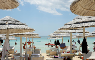 Beautiful beach resort with white straw umbrellas on a blue sky and white clouds. On the background...