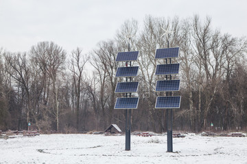 Ecology Power Conservation Concept. Solar station stands in a park on a winter cloudy day. Solar Panels Farm (solar cell) with sunlight.