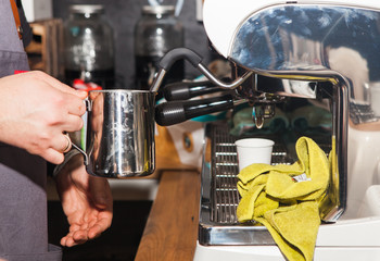 Coffee shop in Los Angeles 19. June. 2019.  Close-up of hands of barista making goof in cafe. Hand is holding an iron mug by the coffee machine.