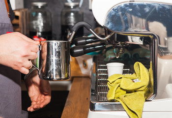 Coffee shop in Los Angeles 19. June. 2019.  Close-up of hands of barista making goof in cafe. Hand is holding an iron mug by the coffee machine.