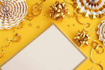 christmas or new year frame decorations and frame in gold colors on yellow  background with copy space for text. Xmas, party,  holiday and celebration concept for postcard or invitation. top view 