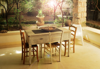White wooden table and chairs set in the backyard of the summer house. Above, a white wooden roof.