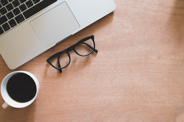 Lifestyle in office on a brown wood table, coffee eyeglasses and computers. Top view.