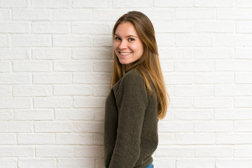 Young woman over white brick wall laughing